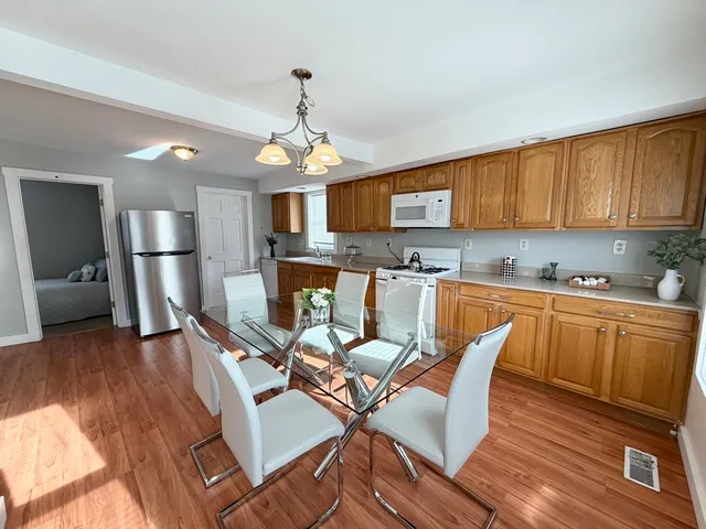 a kitchen with stainless steel appliances granite countertop a stove top oven a sink dishwasher and white cabinets with wooden floor