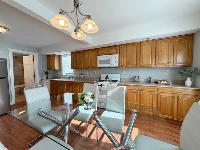 a kitchen with stainless steel appliances granite countertop a sink a stove a refrigerator with white cabinets and wooden floor