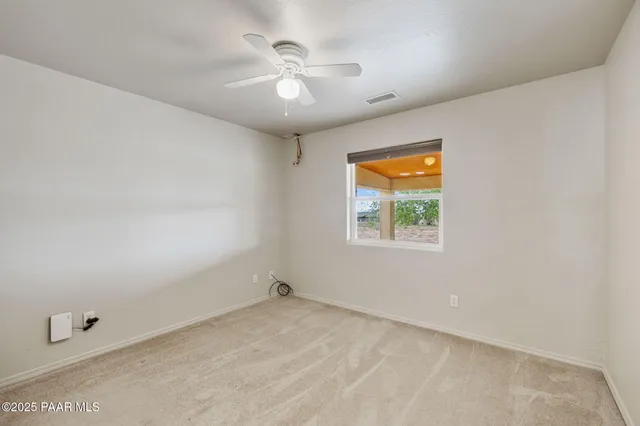 an empty room with windows and ceiling fan