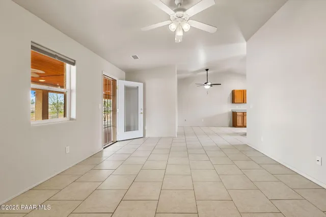 a view of an empty room with chandelier fan