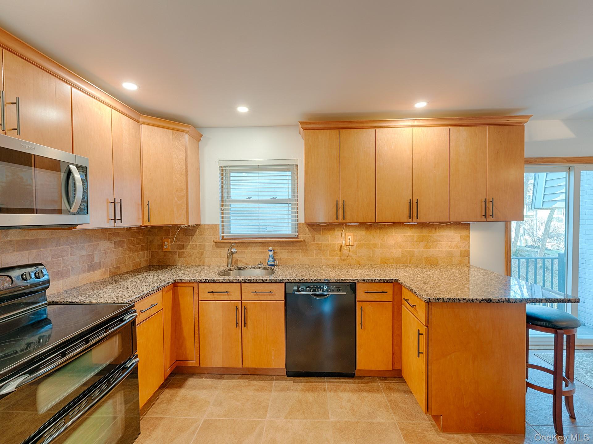 4 Forge Gate Drive, Unit F2B Cold Spring, NY 10516 - Photo 2 of 15 Kitchen with black appliances, light stone countertops, a peninsula, a breakfast bar, and recessed lighting