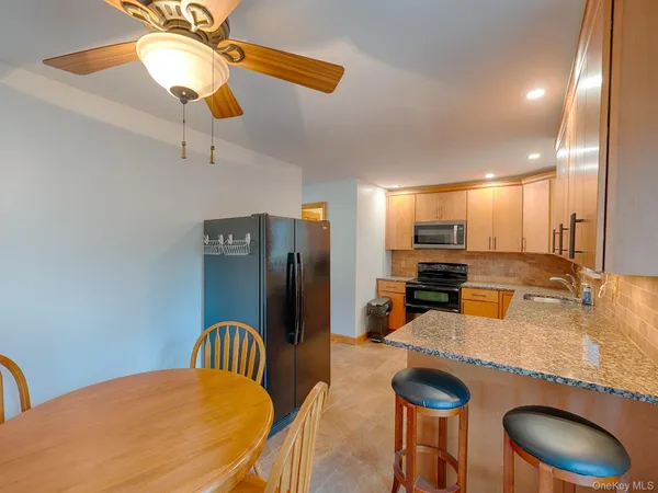 a kitchen with stainless steel appliances granite countertop a dining table chairs and a refrigerator