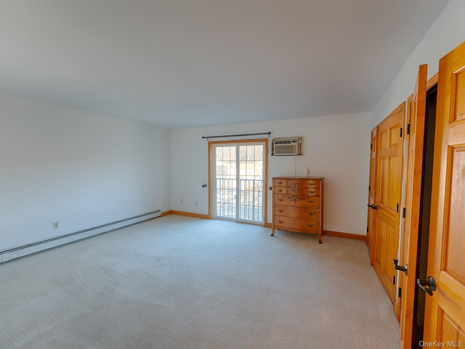 4 Forge Gate Drive, Unit F2B Cold Spring, NY 10516 - Photo 8 of 15 Unfurnished bedroom with light colored carpet, access to outside, a baseboard radiator, and a wall unit AC