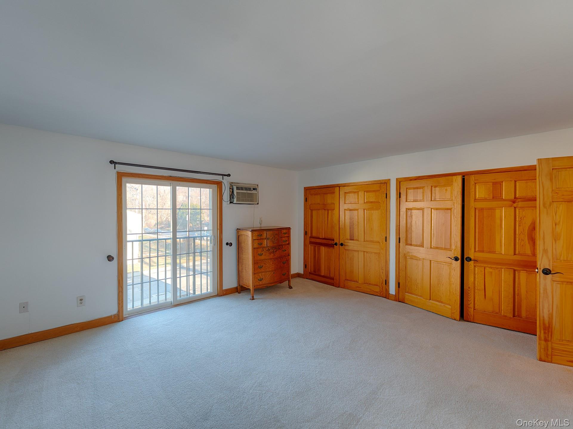 4 Forge Gate Drive, Unit F2B Cold Spring, NY 10516 - Photo 9 of 15 Unfurnished bedroom with multiple closets, light carpet, access to outside, and a wall mounted AC