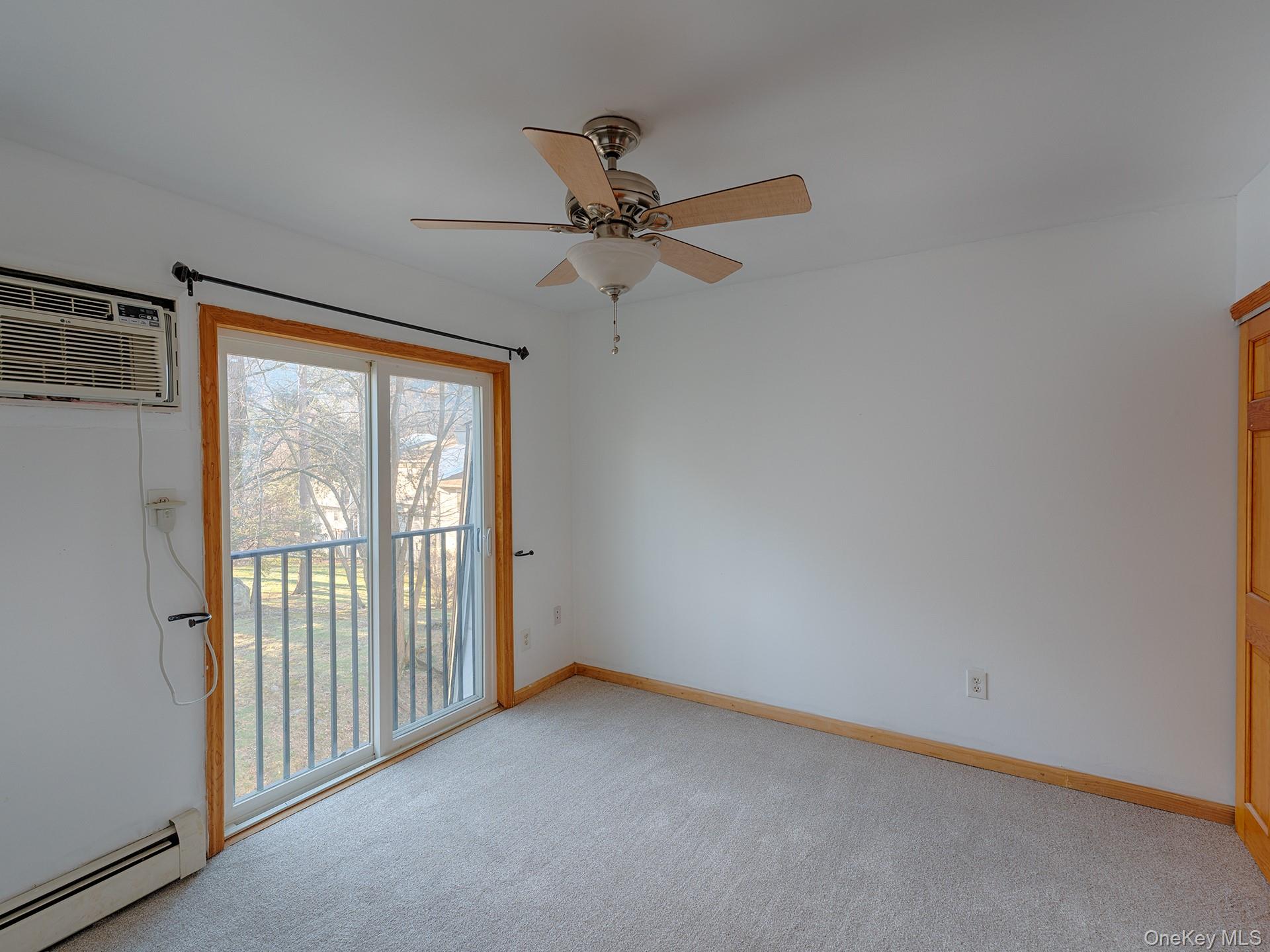 4 Forge Gate Drive, Unit F2B Cold Spring, NY 10516 - Photo 10 of 15 Unfurnished room with baseboard heating, light carpet, a wall unit AC, and ceiling fan