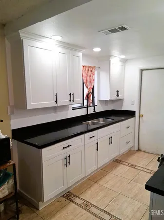 a kitchen with granite countertop white cabinets and a sink