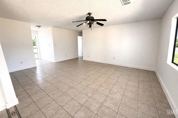 an empty room with a ceiling fan and window