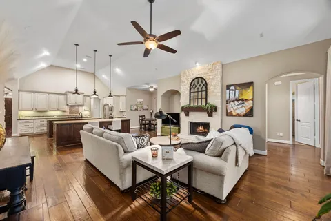 a living room with furniture kitchen view and a wooden floor