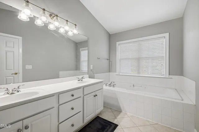 a bathroom with a tub a sink double vanity and a mirror