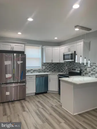 a kitchen with stainless steel appliances granite countertop a refrigerator sink and white cabinets