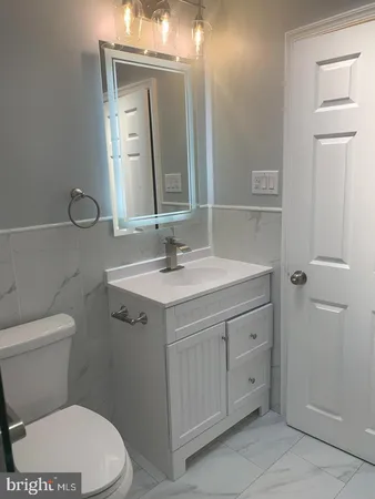 a bathroom with a toilet a sink a vanity and mirror