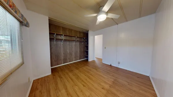 an empty room with wooden floor fan and windows