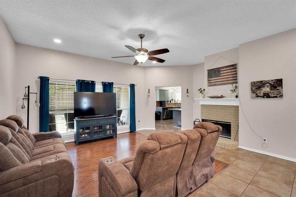 1001 Short Line Boulevard Midlothian, TX 76065 - Photo 18 of 26 Spacious living area featuring wood-finish flooring, a ceiling fan with light fixture, and a brick-surround fireplace with a white mantel
