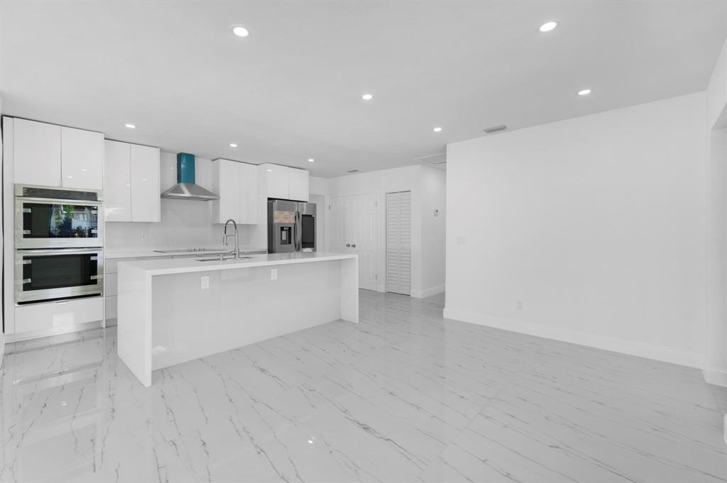 16011 Northwest 38th Court Opa-Locka, FL 33054 - Photo 3 of 38 a large white kitchen with kitchen island a sink a stove a oven with white cabinets