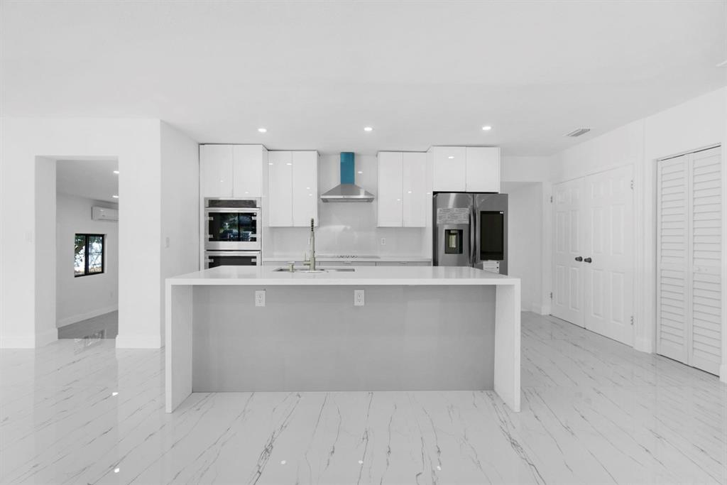 16011 Northwest 38th Court Opa-Locka, FL 33054 - Photo 5 of 38 a large white kitchen with kitchen island a sink stainless steel appliances and cabinets