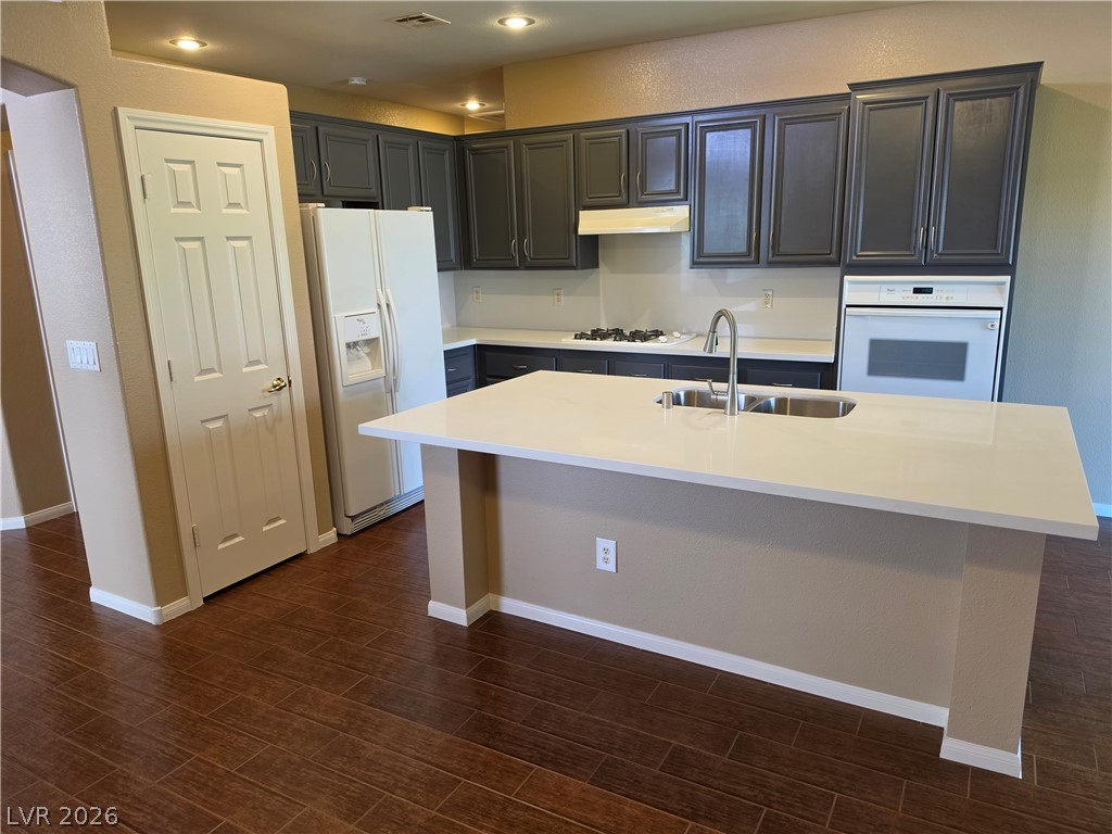 209 Opera House Street Henderson, NV 89012 - Photo 7 of 45 Rich wood flooring grounds this modern kitchen featuring a central island and dark cabinetry.