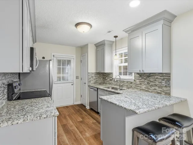 a kitchen with granite countertop kitchen island sink stove and cabinets