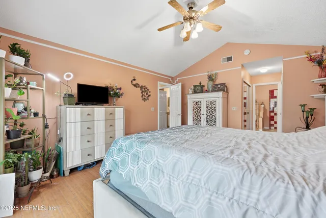 a spacious bedroom with a bed and a flat tv screen on dresser