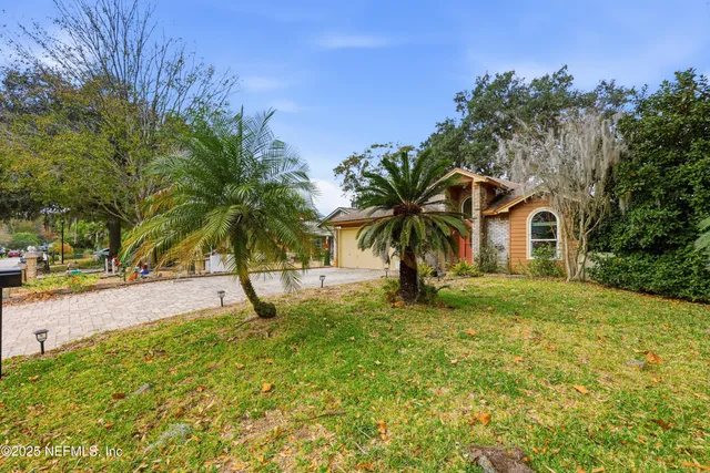 a view of a house with a yard and palm trees