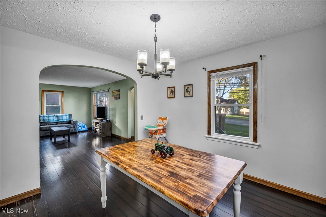 6984 Warren - Sharon Road Brookfield, OH 44403 - Photo 19 of 46 Dining area with arched walkways, dark wood-style floors, a textured ceiling, and a chandelier