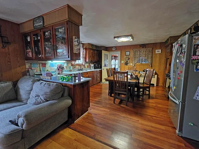 a living room with furniture a fireplace and a dining table with wooden floor