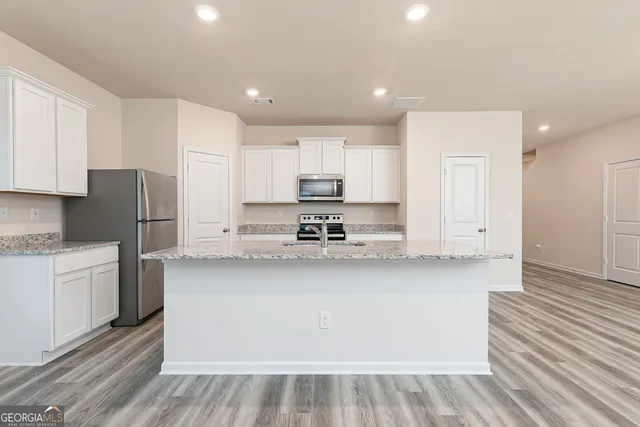 a kitchen with stainless steel appliances granite countertop a refrigerator sink and white cabinets