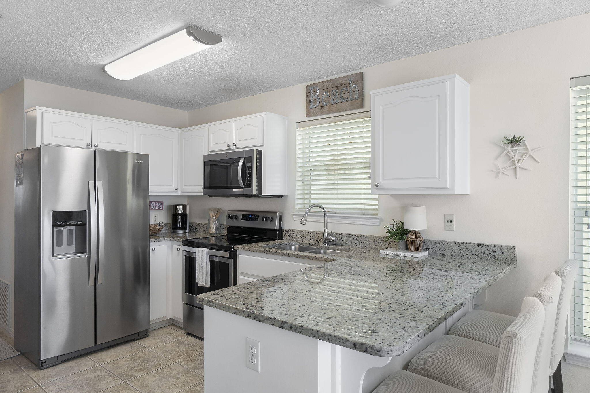 8436 Gulf Boulevard, Unit 321 Navarre, FL 32566 - Photo 25 of 57 a kitchen with stainless steel appliances granite countertop a sink refrigerator and microwave