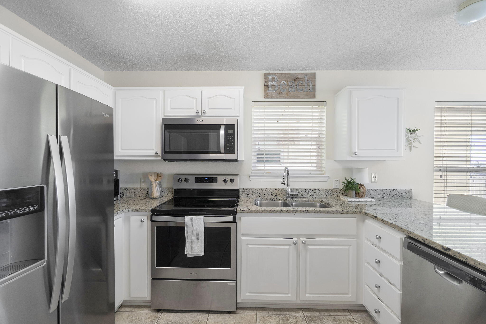 8436 Gulf Boulevard, Unit 321 Navarre, FL 32566 - Photo 26 of 57 a kitchen with white cabinets and stainless steel appliances