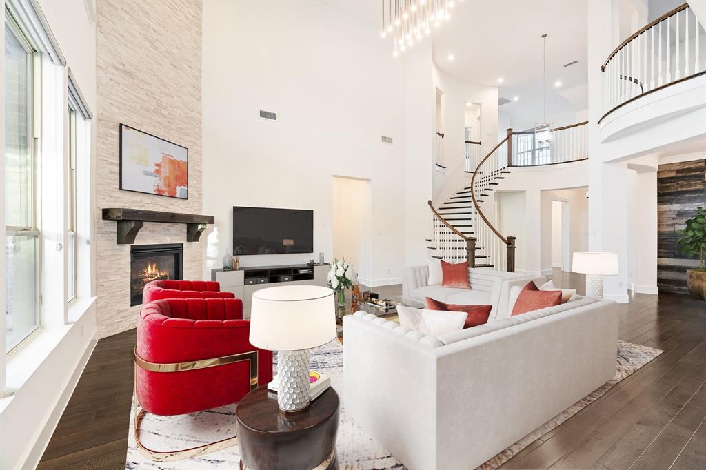 2441 Flat Creek Road Frisco, TX 75036 - Photo 3 of 34 Living area featuring a stone fireplace, a high ceiling, dark wood finished floors, and stairway