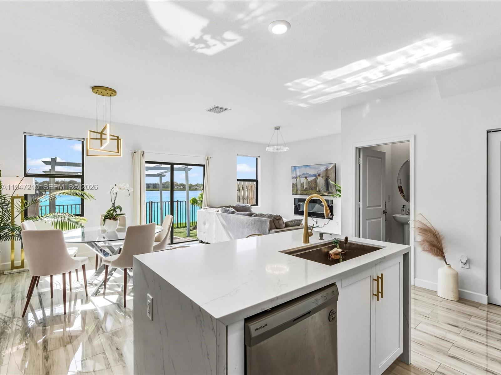 544 Northeast 206th Lane Miami, FL 33179 - Photo 6 of 48 a living room with kitchen island furniture a chandelier fan and a kitchen view