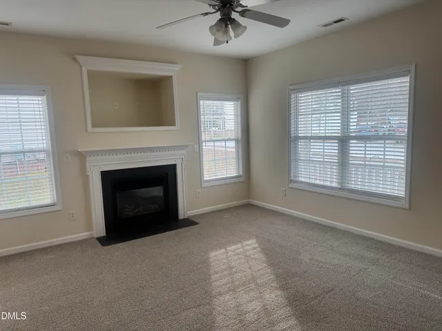 an empty room with windows and fireplace