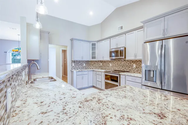 a kitchen with stainless steel appliances granite countertop a stove refrigerator and microwave