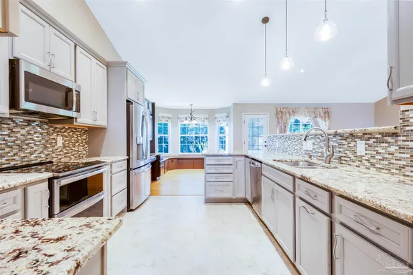 a large kitchen with stainless steel appliances kitchen island granite countertop a stove top oven a sink dishwasher a dining table and chairs with wooden floor