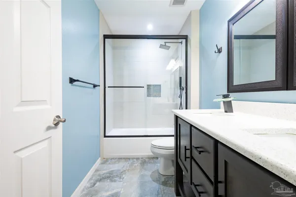 a bathroom with a granite countertop sink a mirror and a shower