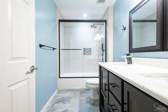 a bathroom with a granite countertop sink a mirror and a shower