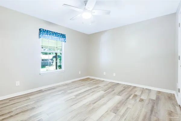 an empty room with windows and fan