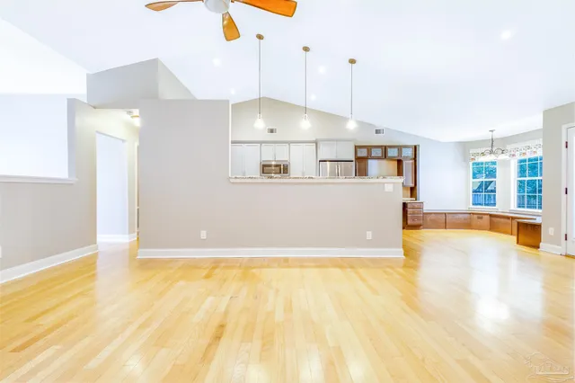 a view of an empty room with window and wooden floor