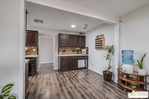 a kitchen with granite countertop a refrigerator cabinets and wooden floor