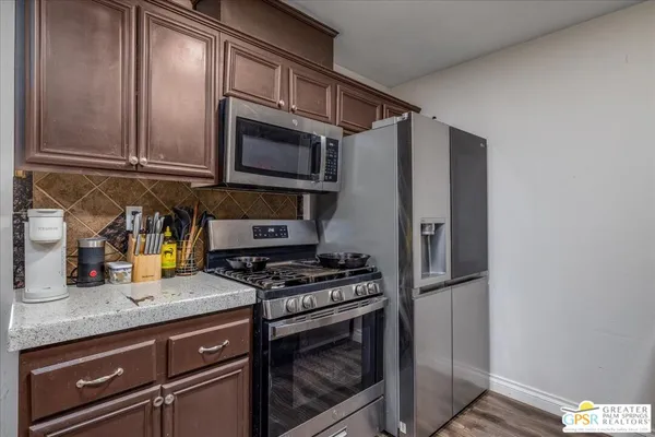 a kitchen with stainless steel appliances granite countertop a refrigerator a stove and a sink