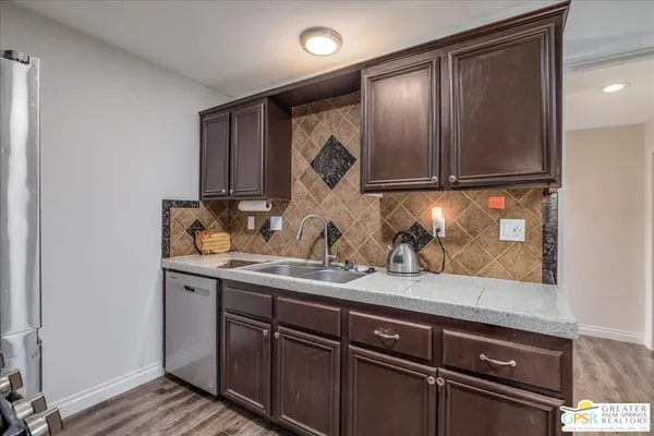 a sink with granite countertop cabinets and a wooden floor