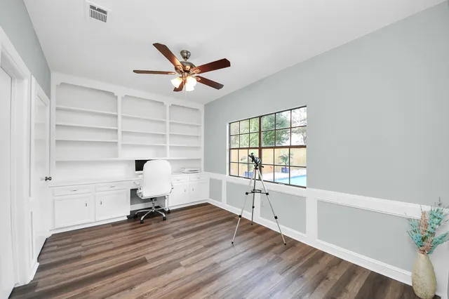 a view of empty room with wooden floor and fan