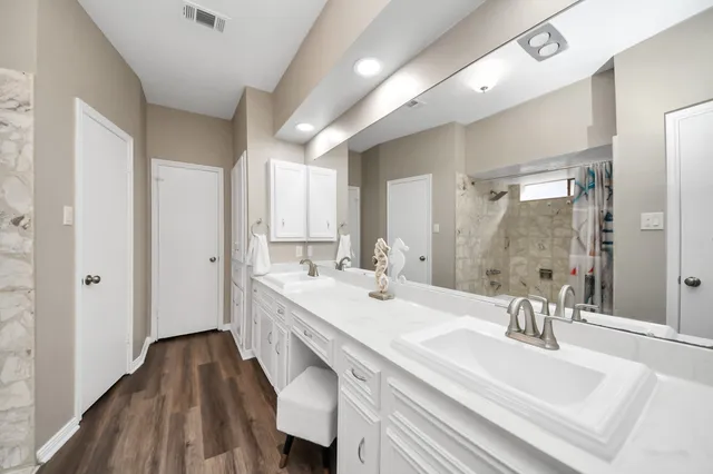 a spacious bathroom with a double vanity sink a mirror and a bathtub