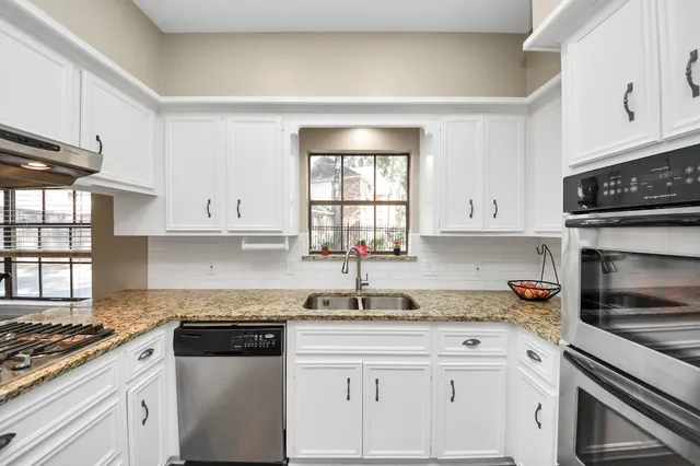 a kitchen with granite countertop white cabinets and appliances