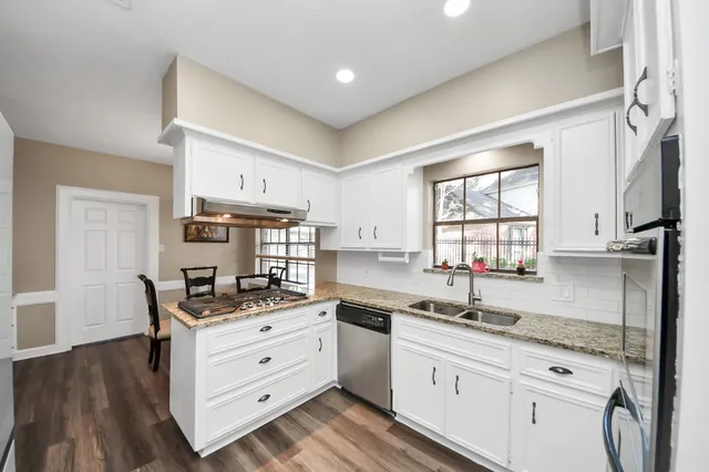 a kitchen with granite countertop a sink a counter space appliances and cabinets
