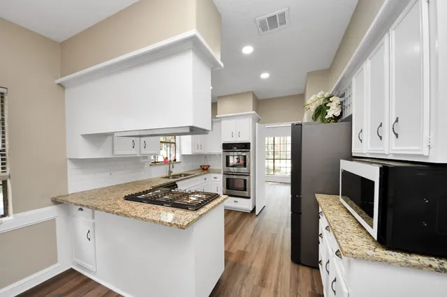 a kitchen with stainless steel appliances granite countertop a stove refrigerator and a microwave oven