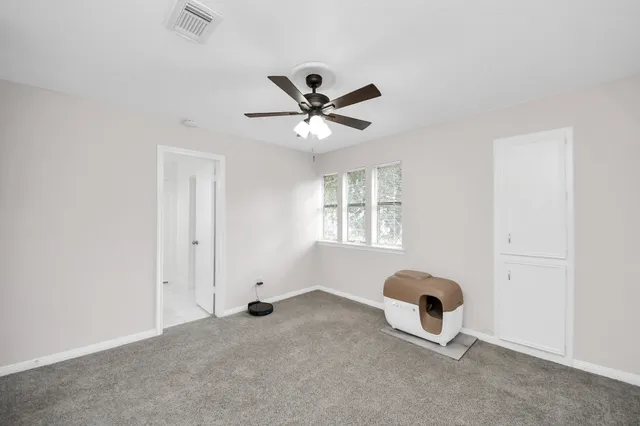 an empty room with windows and ceiling fan