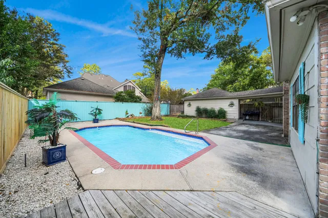 a view of a swimming pool with a patio and a yard