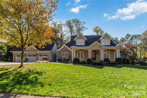 a front view of a house with a garden and trees