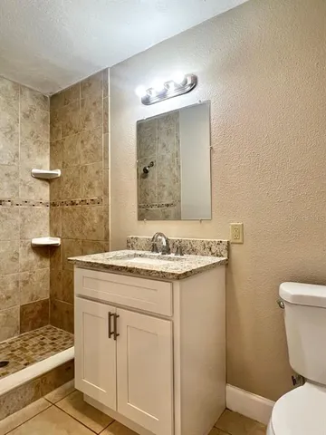 a bathroom with a granite countertop sink toilet and shower