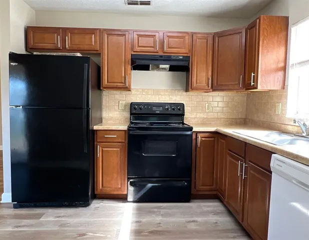 a kitchen with stainless steel appliances wooden cabinets and a stove top oven